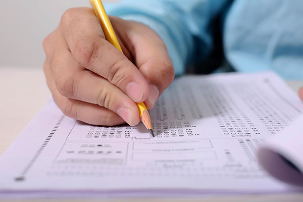 close up of a hand holding a pencil taking a multiple choice test, filling in answer sheet