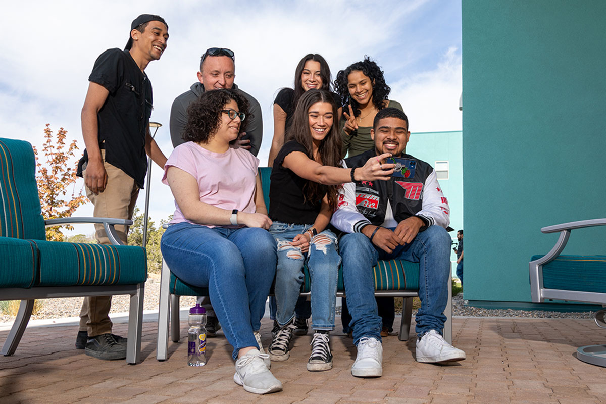 Group of SJC Students sitting together for a selfie outside of housing